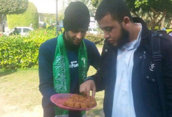 A Palestinian serves baked goods to a passerby in Gaza in celebration of the Jerusalem terror attack.