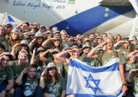 New immigrants from USA and Canada salute and hold up Israeli flags as they arrive in a special "Soldier Aliyah Flight