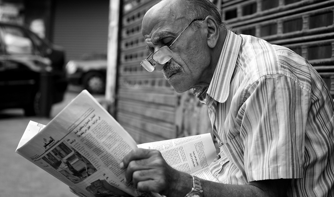 Man reading newspaper in Arabic