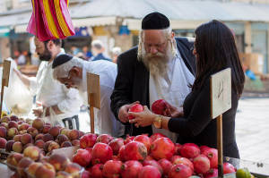 La compra de granadas, un alimento tradicional de Rosh Hashaná, para Rosh Hashaná en el mercado Mahane Yehuda de Jerusalén.  (Foto: Noam Revkin Fenton / Flash90)