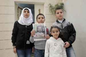 Family members of Ibrahim Akkari hold his picture as a martyr  after he was shot following his driving his car into a group of people at a Jerusalem light rail station. 