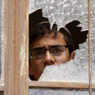 Jewish man peers through broken window. (Photo: Nati Shohat/Flash90)