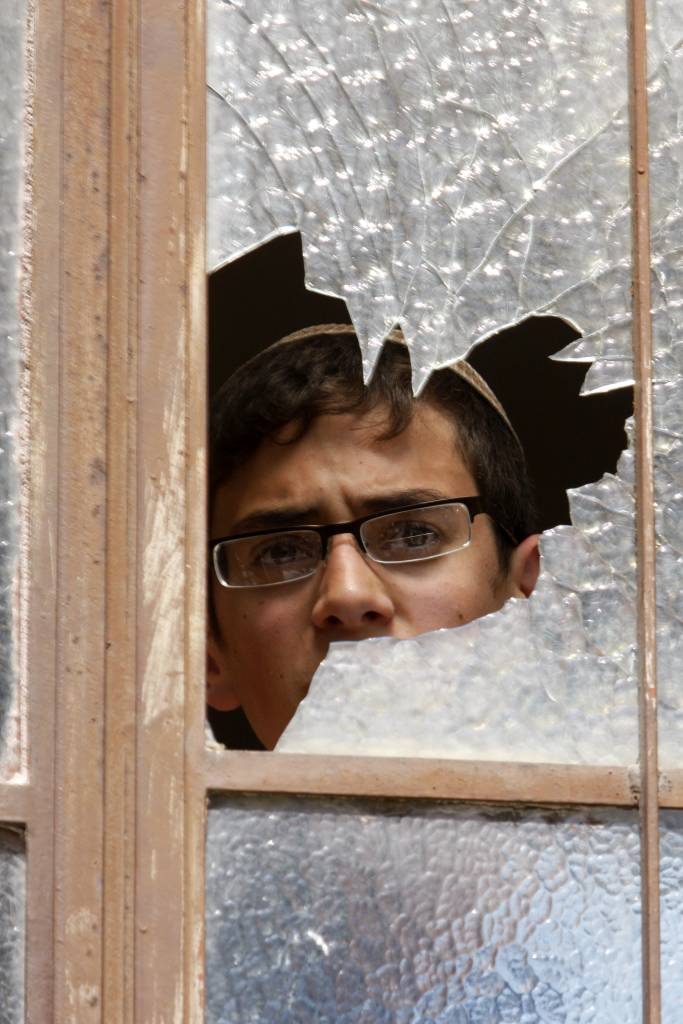 Jewish man peers through broken window. (Photo: Nati Shohat/Flash90)