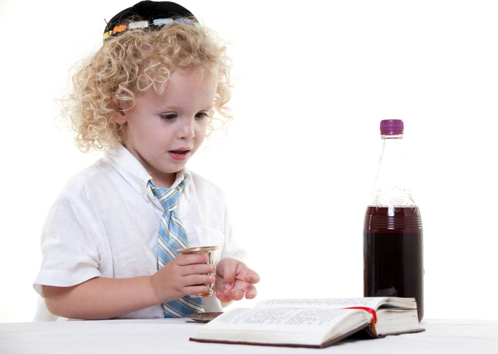 A Jewish boy recites the prayer over grape juice. (Photo: Geo Martinez/Shutterstock)