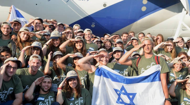 New immigrants from USA and Canada salute and hold up Israeli flags as they arrive in a special "Soldier Aliyah Flight