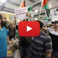 Foreign and Palestinian activists hold Palestinian flags as they march through an Israeli supermarket