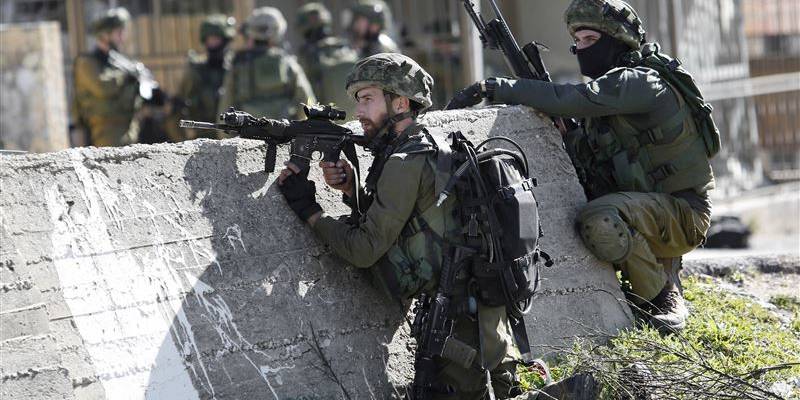 IDF soldiers take positions during a raid to arrest a Palestinian