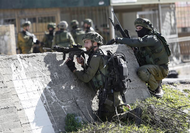 IDF soldiers take positions during a raid to arrest a Palestinian