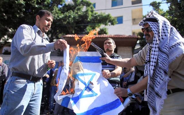 Palestinian protesters burn an Israeli flag