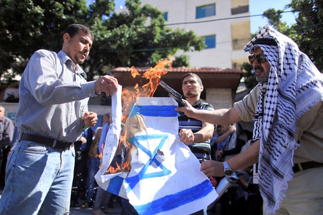 Palestinian protesters burn an Israeli flag