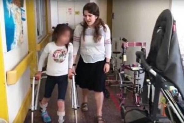 A National Civil Service volunteer helps a disabled child. (Screenshot)