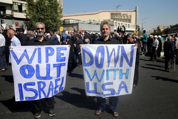 Two Iranians hold anti-US and anti-Israeli placards