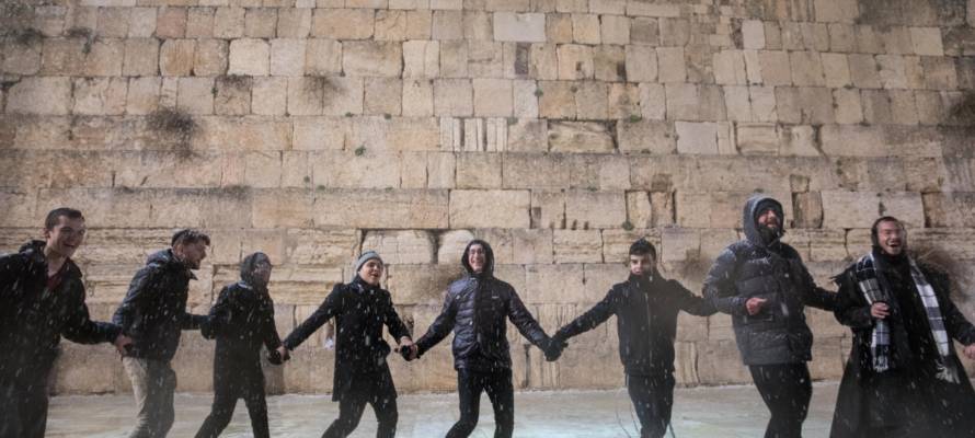 Men dance in the snow at the Western Wal, in Jerusalem. (Noam Rivkin Fenton/Flash90)