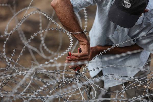 Palestinian tires to breach barbed wire fence installed along the border. (Wissam Nassar/Flash90)