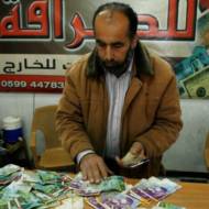Palestinian man displays Israeli shekels. (Abed Rahim Khatib/Flash90)