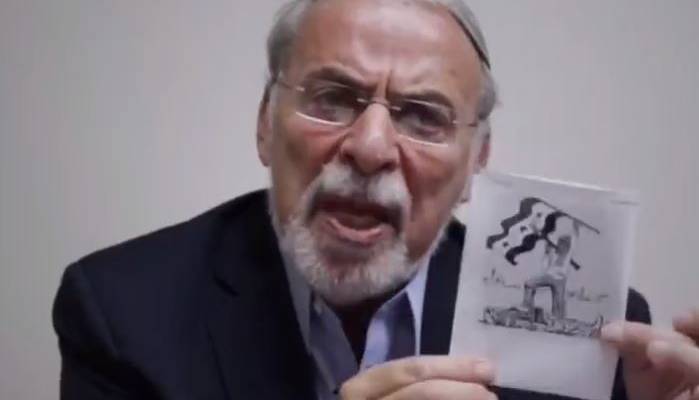 Dov Hikind holds cartoon by Holocaust denier