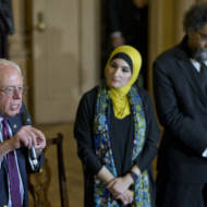 Linda Sarsour, center, listens as Democratic presidential candidate Bernie Sanders speaks.
