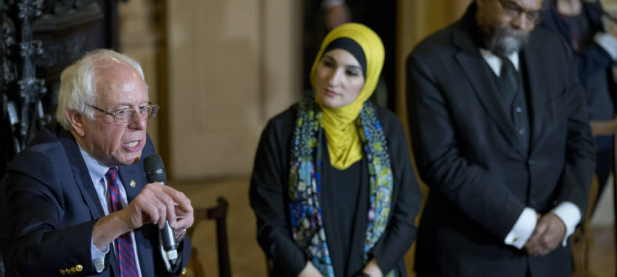 Linda Sarsour, center, listens as Democratic presidential candidate Bernie Sanders speaks.