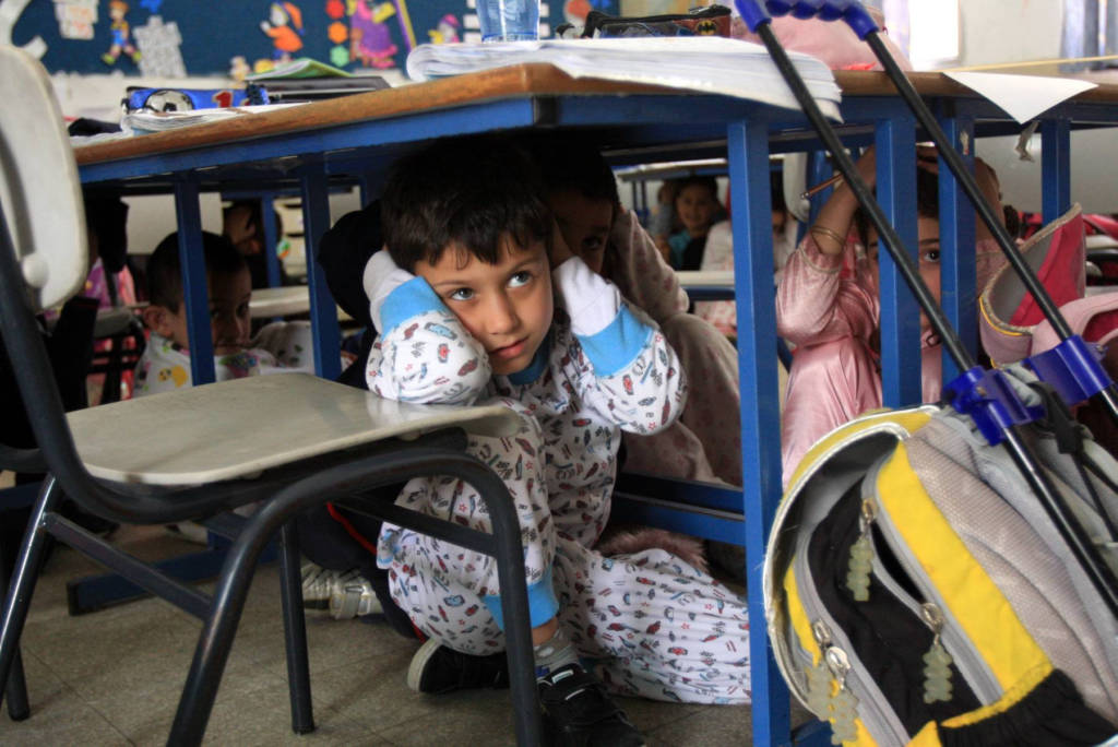 At a school in Ashkelon, children hide under chairs and tables while practicing what to do during an eventual Qassam Rocket attack. (Edi Israel/Flash90)