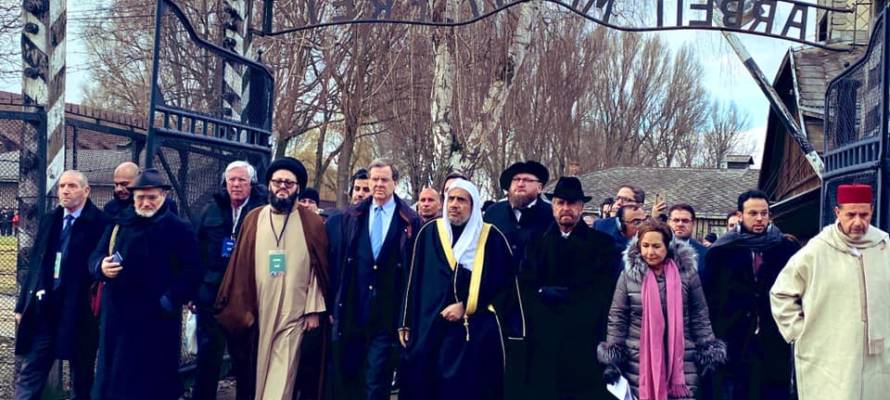 Secretary General of the Muslim World League Dr. Mohammad Al-Issa, center, wearing a white head-covering, and AJC CEO David Harris, next to him, left, lead delegation entering through the Auschwitz gate at the start of a historic visit to the Nazi death camp, Jan. 23, 2020.