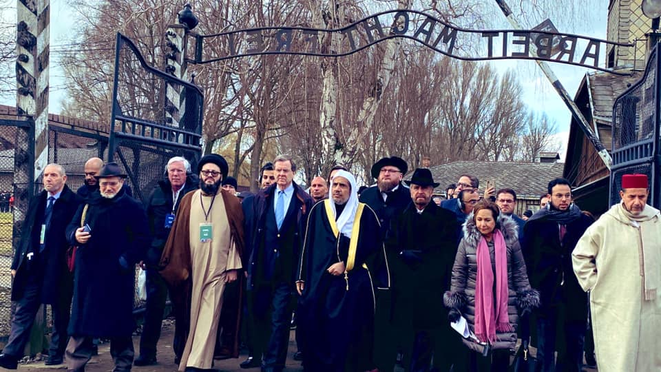 Secretary General of the Muslim World League Dr. Mohammad Al-Issa, center, wearing a white head-covering, and AJC CEO David Harris, next to him, left, lead delegation entering through the Auschwitz gate at the start of a historic visit to the Nazi death camp, Jan. 23, 2020.