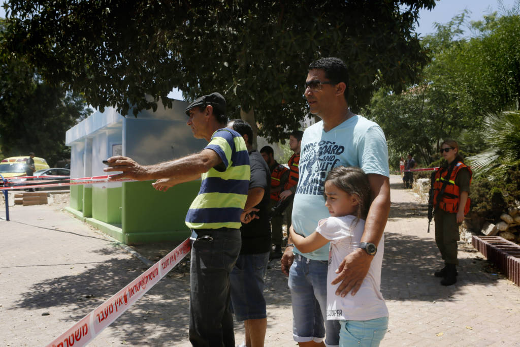 Israelis near the remains of a rocket fired by Palestinian terrorists