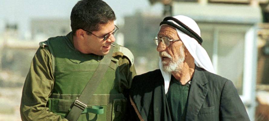 An Israeli soldier walks with a senior
