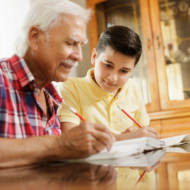 elderly man helps boy with homework